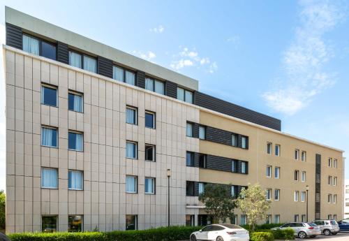 a large building with cars parked in front of it at B&B HOTEL Montpellier Centre Le Millénaire in Montpellier