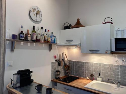 une cuisine avec un évier et une horloge murale dans l'établissement LOFT Villa Anjou, à Soulac-sur-Mer