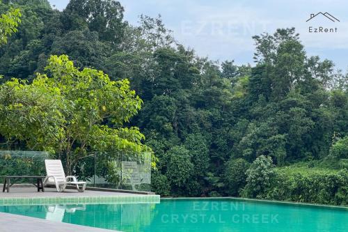 Taiping Chill Retreat Homestay near Lake Garden في تايبينغ: مقعد بجوار حمام السباحة أمام الغابة