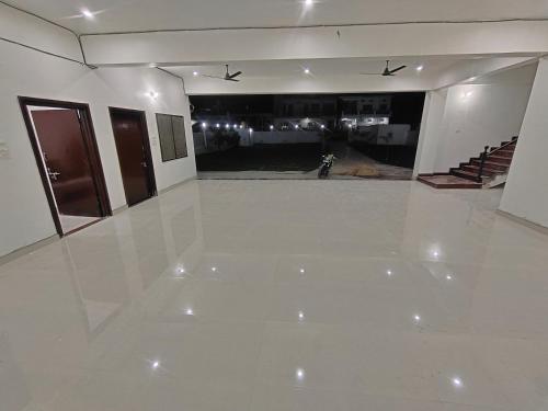 a large empty room with a white floor and stairs at ANAND BHAWAN i in Shivāpur