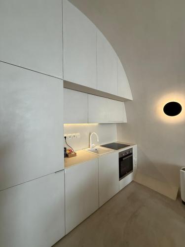 a white kitchen with white cabinets and a sink at Aesthesis Boutique Villas Fira in Fira