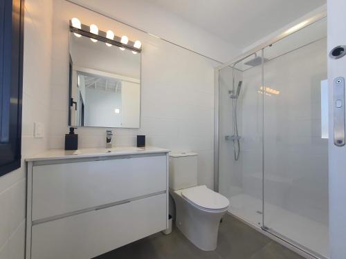 a white bathroom with a toilet and a shower at Casa Fielato in Los Barros