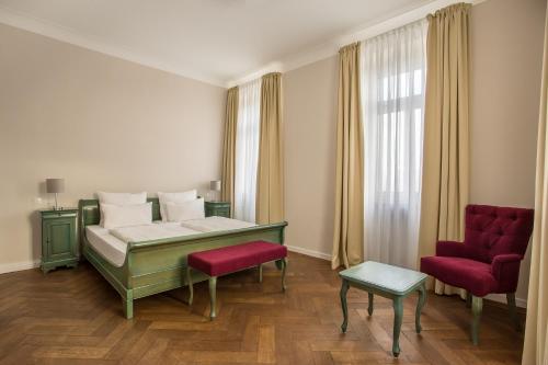 a bedroom with a bed and two red chairs at Hotel Annaberg in Bad Dürkheim