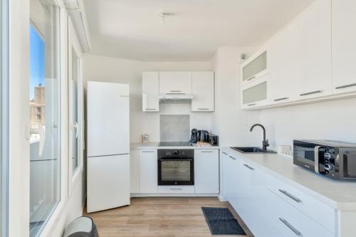 une cuisine blanche avec des armoires et des appareils blancs dans l'établissement GuestReady - Bright Escape with City Views, à Bobigny