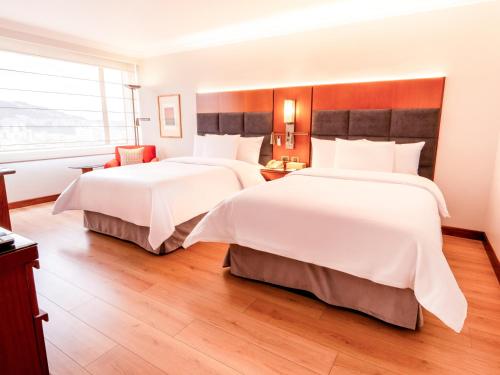 a hotel room with two beds and a window at Swissotel Quito in Quito