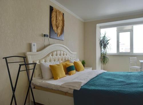 une chambre avec un grand lit blanc avec des oreillers jaunes dans l'établissement Космос-Лайт, à Aqtöbe