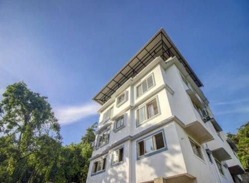a white building with trees in the background at Exotic star 1 BHK 2BHK Apartment in Socorro