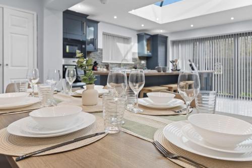 a dining room table with plates and wine glasses at Large 4BR Leicester House, Modern, Sleeps 10, M1&M69, Garden, Fast WiFi, Free Secure Parking, Long Stay & Contractors Welcome in Leicester