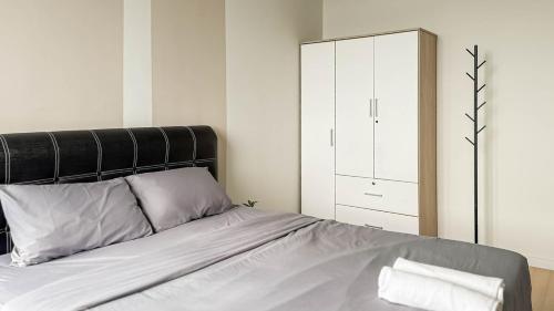 a bedroom with a bed with a black headboard and a cabinet at Sunset Haven Taiping Homestay near Lake Garden TPG in Taiping