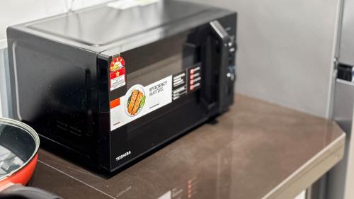 a black microwave sitting on top of a counter at Sunset Haven Taiping Homestay near Lake Garden TPG in Taiping