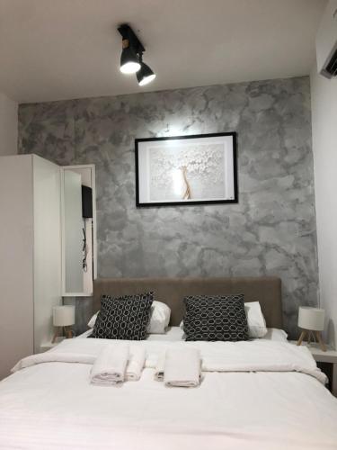 a bedroom with a white bed with a stone wall at Danijela & konak in Zlatibor