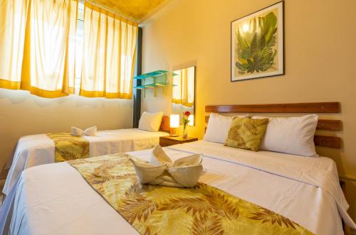 two beds in a room with yellow walls and windows at Hotel Daylu in Iquitos
