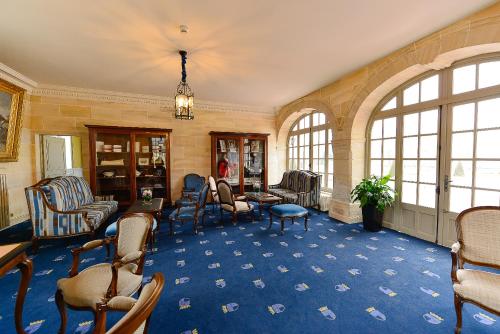 a large room with chairs and tables and windows at Chateau d'Audrieu in Audrieu