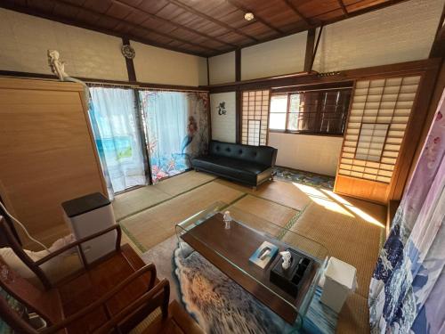 an overhead view of a living room with a couch and a table at 窓際から海と鉄道が見える宿 サウナ プロジェクター カラオケ完備 トリックマーメイド in Ito