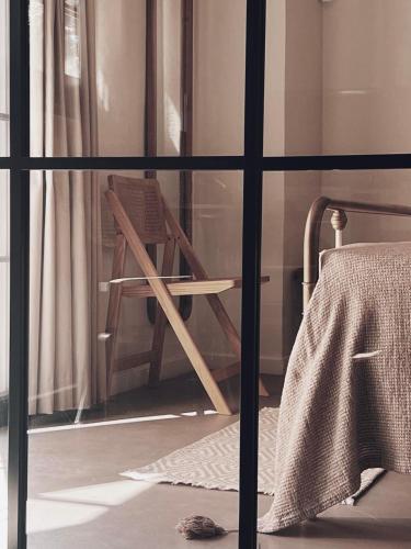 a wooden chair sitting in front of a window at ALFIEA HOME 65m2 & ALFIEA STUDIO 35m2 in Artemida
