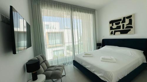 ein Schlafzimmer mit einem Bett und einem Stuhl und einem Fenster in der Unterkunft Luxury 4 bdr Villa Nerida in Klorakas