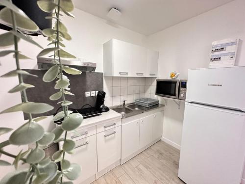 une cuisine avec des armoires blanches et un réfrigérateur blanc dans l'établissement Les 3 Piliers grand T2 confortable avec parking, à Reims