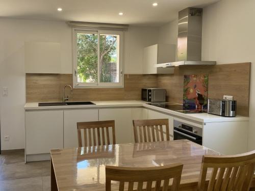 une cuisine avec une table, des chaises et un évier dans l'établissement Les Mûriers 