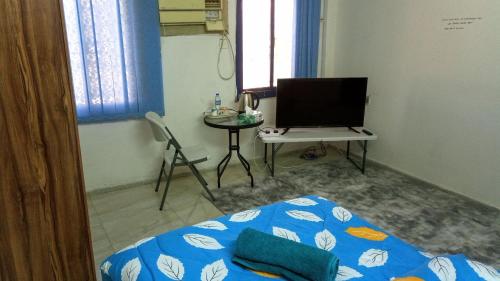 a bedroom with a bed and a table and a tv at SALEM House Hostel Nizwa in Nizwa