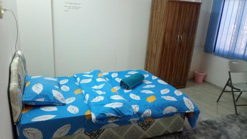a bed with a blue comforter in a room at SALEM House Hostel Nizwa in Nizwa