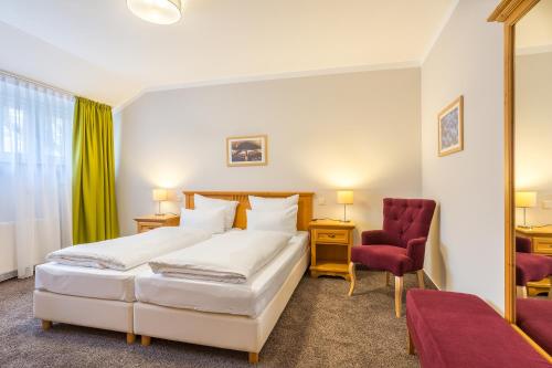 1 dormitorio con 2 camas y silla roja en Hotel Annaberg, en Bad Dürkheim