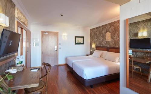 a hotel room with a bed and a desk and a television at Sercotel Hotel President in Figueres