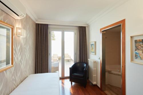 a bedroom with a bed and a chair and a window at Sercotel Hotel President in Figueres