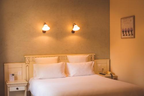 a bedroom with a white bed with two lights above it at Le Mas Du Colombier in Cadenet