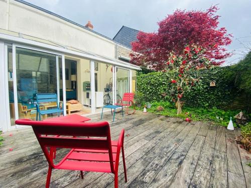 un banc rouge sur une terrasse en bois avec un arbre dans l'établissement Casa Anna, à Angers