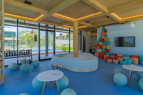 a lobby with tables and chairs and a pool at Cais Eco Residência in Porto De Galinhas