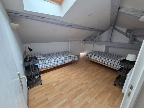 Cette chambre mansardée comprend deux lits et un bureau. dans l'établissement Appartement du Palais Longchamps, à Marseille
