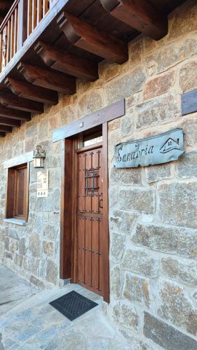 a stone building with a wooden door and a sign at Casa Rural Sanabria in Otero de Sanabria