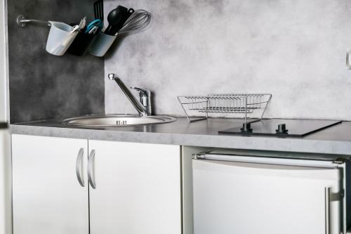 une cuisine avec des armoires blanches et un évier dans l'établissement La Rose Des Vents - Studio - Arago - Vue mer, à Les Sables-dʼOlonne