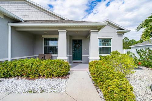 a white house with a green door and bushes at Heated Pool 4BR Retreat Family Friendly in Carlton