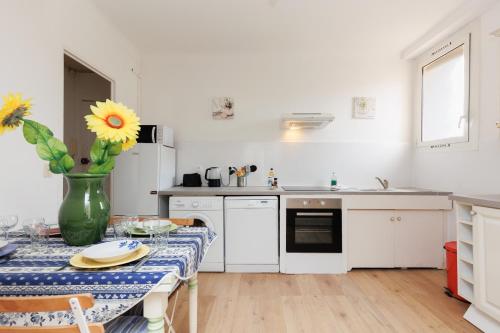 une cuisine avec une table avec un vase de fleurs dessus dans l'établissement IMMOGROOM - 5 min from beaches - Suquet - AC, à Cannes