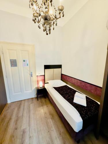a bedroom with a large bed and a chandelier at Hotel Pension Baron am Schottentor in Vienna