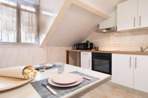 une cuisine avec une table recouverte de assiettes roses dans l'établissement Le Vitry - Calme, terrasse, proche Paris, à Vitry-sur-Seine