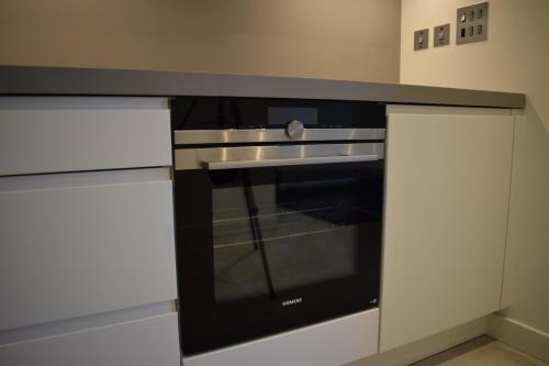 a black oven in a kitchen with white cabinets at Luxury Studio retreat in Gibraltar