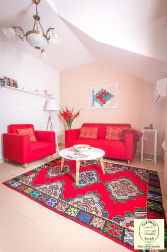 a living room with two red couches and a table at Zornića Kuća in Ba°evac