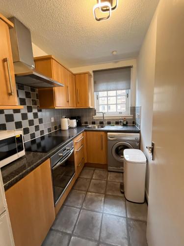 a kitchen with wooden cabinets and a washer and dryer at Causewayside Free parking in Edinburgh