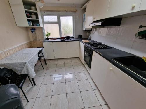 a kitchen with a table and a stove top oven at Cosy rooms in London in London