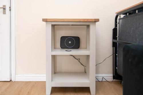 a small white table with a speaker on a shelf at Lovely refurbed 4 bed house in Black Country in Tipton
