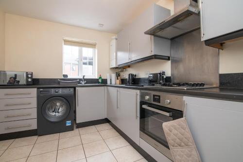 a kitchen with a washer and a washing machine at Lovely refurbed 4 bed house in Black Country in Tipton