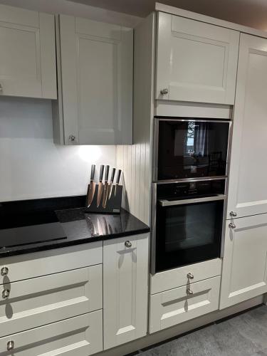 a kitchen with white cabinets and a black counter top at Lower Carhullan in Penrith
