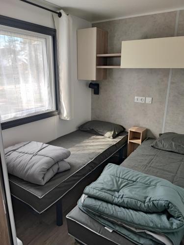 une petite chambre avec deux lits et une fenêtre dans l'établissement MOBIL - HOME 2 6p Bois de Bayadene, à Piriac-sur-Mer