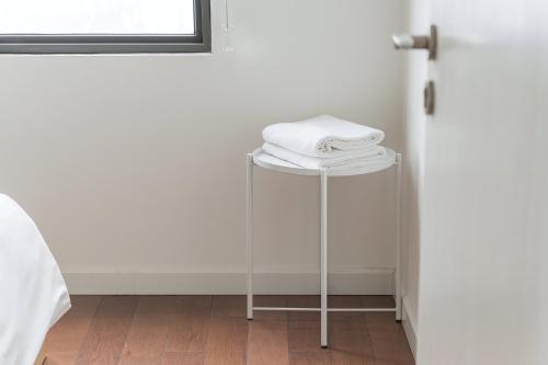 a stool with white towels on it next to a door at HN ETH Vinhomes D'capitale Resident - Tran Duy Hung St in Hanoi