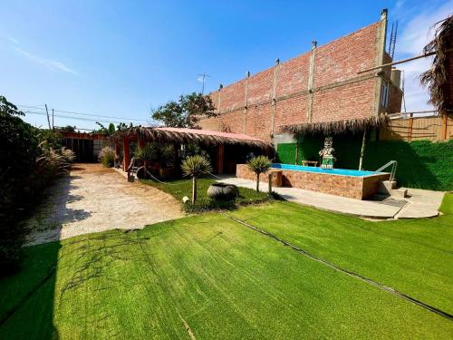 a backyard with a swimming pool and a brick building at Casa Colpa Tiki in Chincha