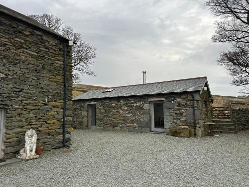 a stone building with a cat sitting in front of it at Lower Carhullan in Penrith
