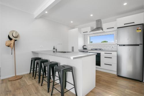 a kitchen with a white counter top and stools at Sandy Serenity in Waihi Beach