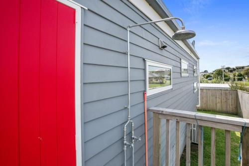 a red door on the side of a house at Sandy Serenity in Waihi Beach
